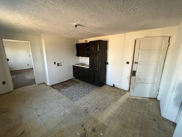 1908 Mccallie Ave, Chattanooga, TN 37404 - kitchen featuring light flooring, a textured ceiling, dark brown cabinetry, and baseboards