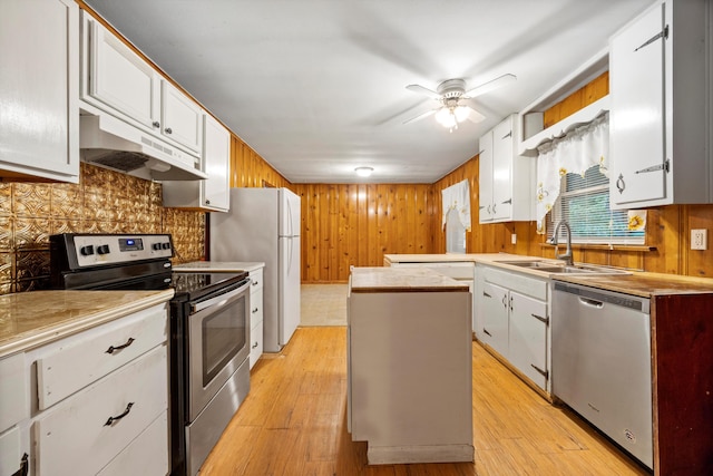 2524 Spring Place Rd SE, Cleveland, TN 37323 - kitchen with under cabinet range hood, appliances with stainless steel finishes, a sink, light countertops, and wooden walls