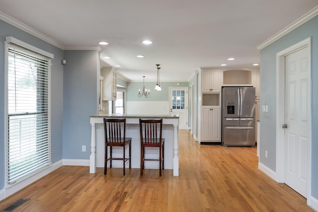 2195 Ooltewah Ringgold Rd, Ooltewah, TN 37363 - kitchen with stainless steel fridge with ice dispenser, crown molding, a chandelier, light wood-style floors, and a kitchen bar
