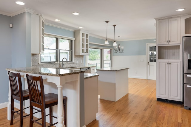 2195 Ooltewah Ringgold Rd, Ooltewah, TN 37363 - kitchen with glass insert cabinets, a peninsula, light stone counters, light wood-type flooring, and ornamental molding