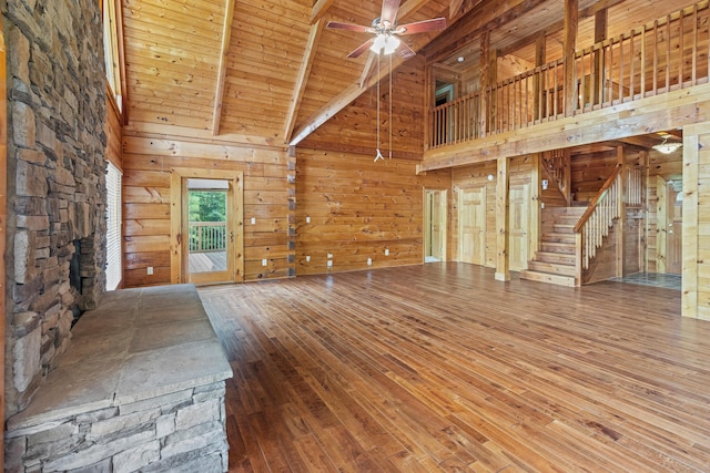 7524 Banther Rd, Harrison, TN 37341 - unfurnished living room featuring high vaulted ceiling, hardwood / wood-style floors, stairway, wood walls, and ceiling fan