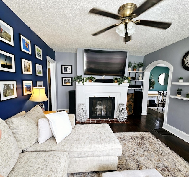 503 S Lovell Ave, Chattanooga, TN 37412 - living area featuring wood finished floors, ceiling fan, a fireplace with flush hearth, arched walkways, and a textured ceiling