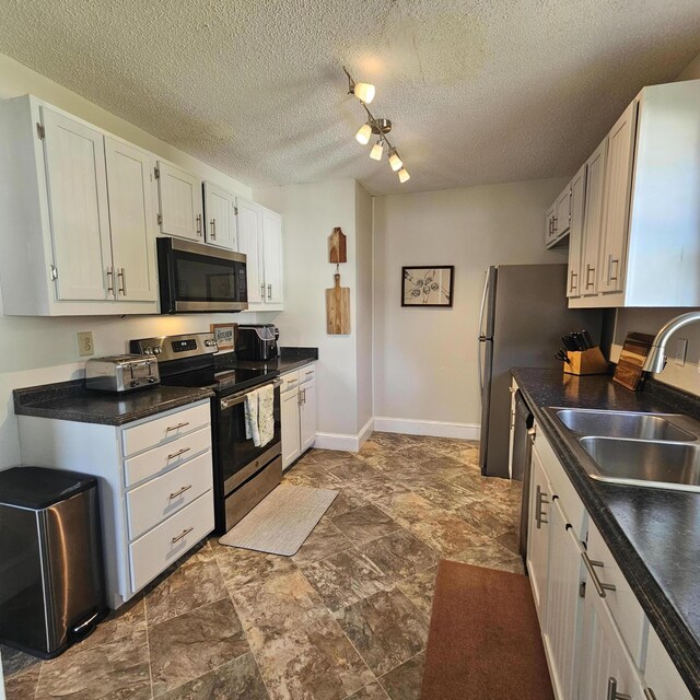 503 S Lovell Ave, Chattanooga, TN 37412 - kitchen with stainless steel appliances, dark countertops, stone finish floors, white cabinetry, and a textured ceiling