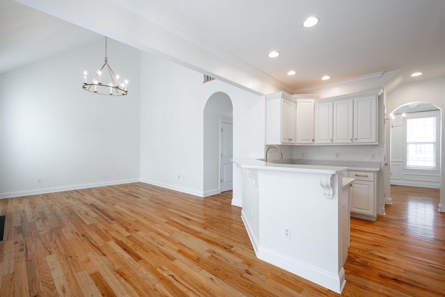 8539 Lexie Ln, Ooltewah, TN 37363 - kitchen with arched walkways, a kitchen bar, light countertops, white cabinets, and a chandelier