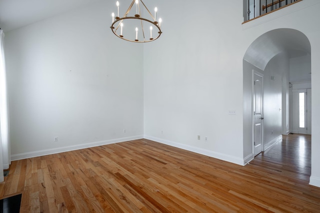 8539 Lexie Ln, Ooltewah, TN 37363 - empty room featuring wood finished floors, arched walkways, a chandelier, and a high ceiling