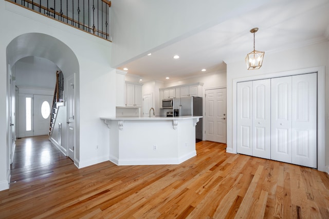 8539 Lexie Ln, Ooltewah, TN 37363 - kitchen with appliances with stainless steel finishes, a peninsula, light wood-style floors, a breakfast bar area, and ornamental molding