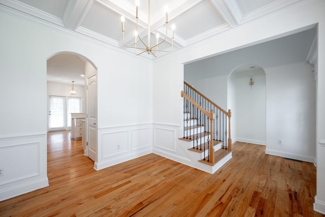 8539 Lexie Ln, Ooltewah, TN 37363 - empty room with arched walkways, coffered ceiling, light wood-type flooring, a chandelier, and a wainscoted wall