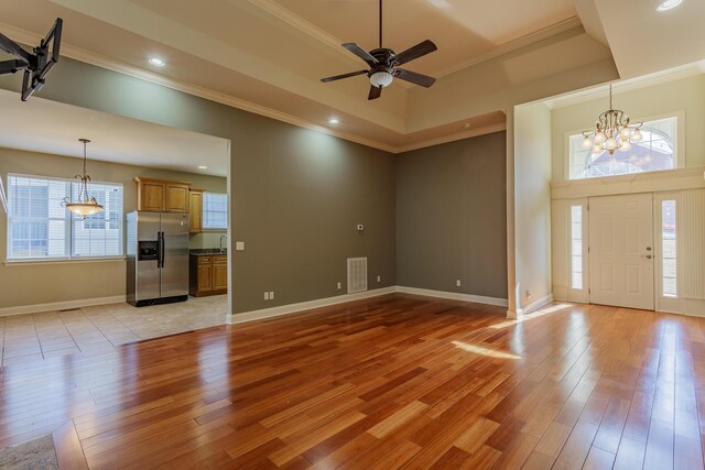 2367 Lake Mist Dr, Chattanooga, TN 37421 - unfurnished living room with a chandelier, crown molding, light wood-style floors, a ceiling fan, and a tray ceiling