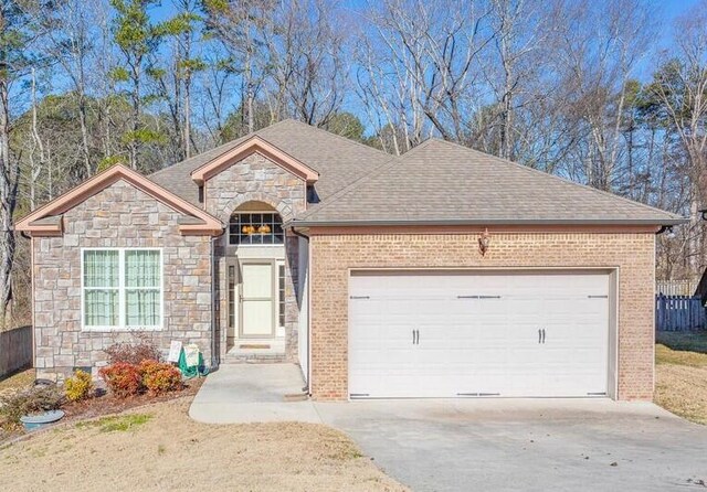 2367 Lake Mist Dr, Chattanooga, TN 37421 - view of front of property featuring stone siding, a garage, roof with shingles, and driveway