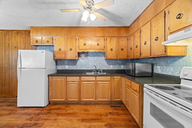 1307 Park Forrest Dr, Fort Oglethorpe, GA 30742 - kitchen with white appliances, under cabinet range hood, a textured ceiling, dark countertops, and dark wood finished floors