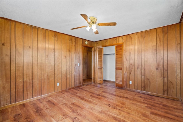 1307 Park Forrest Dr, Fort Oglethorpe, GA 30742 - unfurnished bedroom with wood finished floors, wooden walls, a textured ceiling, a ceiling fan, and a closet