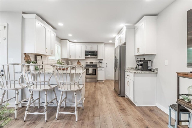 918 Old Lafayette Rd, Chickamauga, GA 30707 - kitchen featuring appliances with stainless steel finishes, white cabinetry, a peninsula, light stone counters, and light wood-style floors