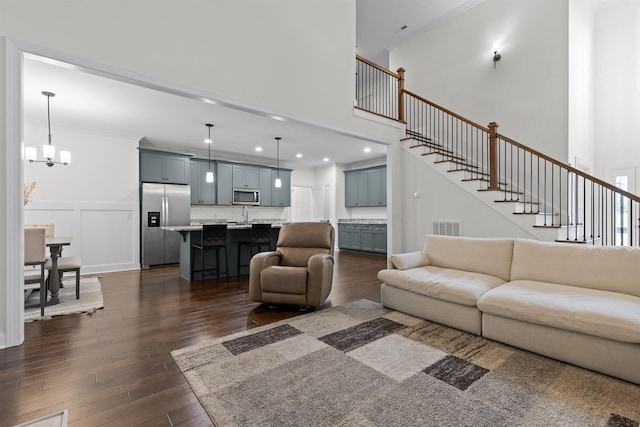 6434 Satjanon Dr, Ooltewah, TN 37363 - living area featuring dark wood-style flooring, a chandelier, crown molding, stairway, and a towering ceiling