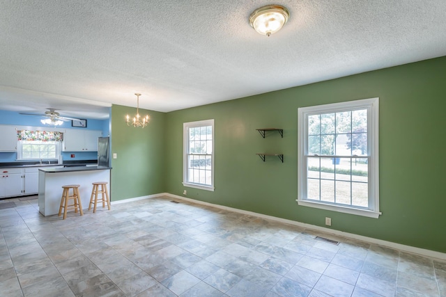 105 Joyce Ave, Red Bank, TN 37415 - kitchen with freestanding refrigerator, dark countertops, a chandelier, white cabinetry, and a textured ceiling