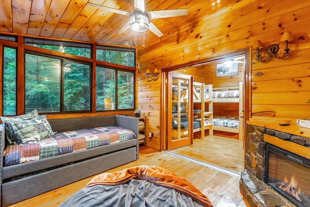 879 Amy Creek Cir, Ellijay, GA 30540 - living area with wood-type flooring, wood walls, a stone fireplace, a ceiling fan, and wood ceiling