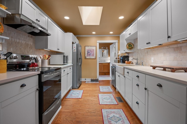 3412 Fairmount Pike, Signal Mountain, TN 37377 - kitchen featuring stainless steel appliances, a skylight, light wood finished floors, tasteful backsplash, and crown molding