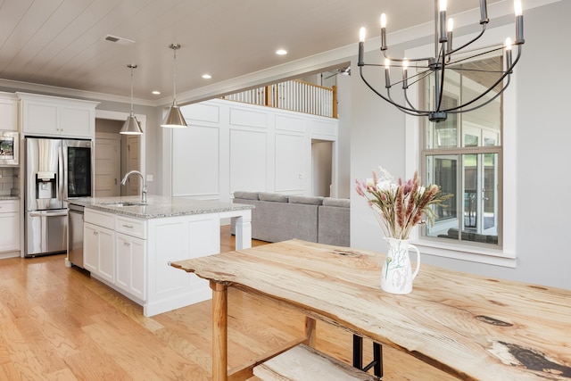 10607 Flicker Way, Apison, TN 37302 - kitchen featuring appliances with stainless steel finishes, white cabinetry, light wood-style floors, light stone counters, and a center island with sink