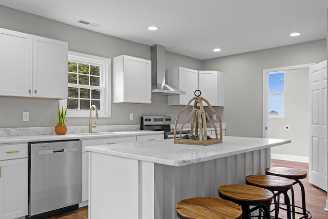 2001 Vine St, Chattanooga, TN 37404 - kitchen featuring stainless steel appliances, wall chimney range hood, a kitchen island, a kitchen bar, and dark wood finished floors