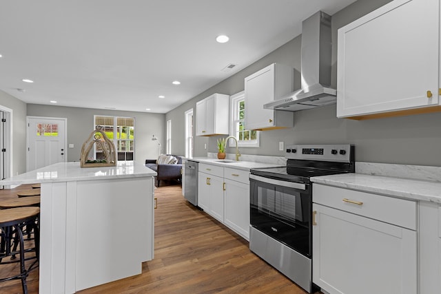 2001 Vine St, Chattanooga, TN 37404 - kitchen featuring appliances with stainless steel finishes, wall chimney exhaust hood, a kitchen breakfast bar, a center island, and dark wood-style flooring