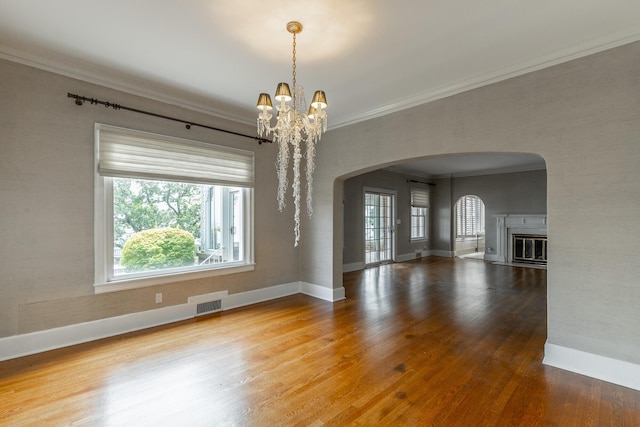 208 S Palisades Dr, Signal Mountain, TN 37377 - unfurnished living room with arched walkways, healthy amount of natural light, ornamental molding, wood finished floors, and a chandelier