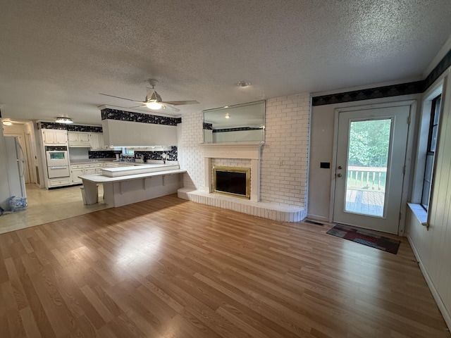 30551 Al Al Unit 71, Bryant, AL 35958 - unfurnished living room featuring a textured ceiling, ceiling fan, light wood-type flooring, and a fireplace