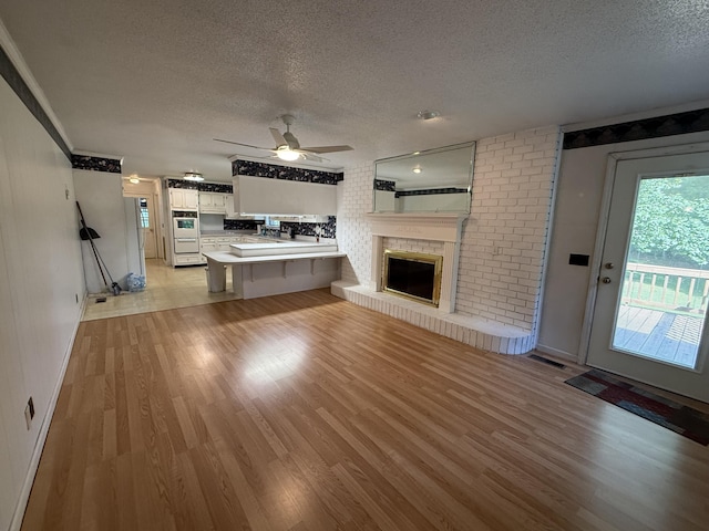 30551 Al Al Unit 71, Bryant, AL 35958 - unfurnished living room featuring a textured ceiling, a ceiling fan, light wood-style flooring, and a fireplace