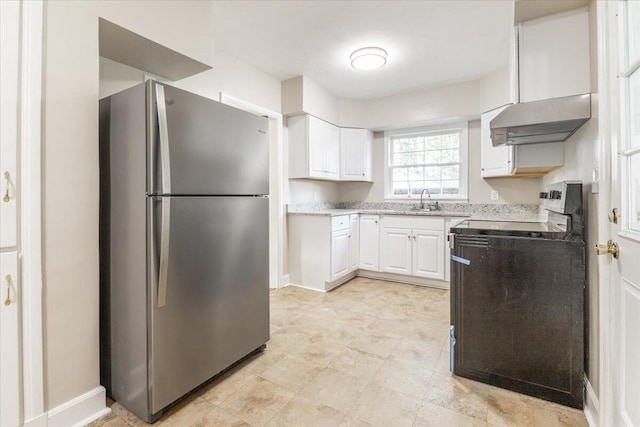 147 Kirby St, Summerville, GA 30747 - kitchen with freestanding refrigerator, under cabinet range hood, white cabinetry, range, and light stone countertops
