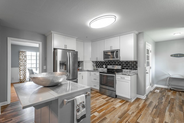 409 Caraway Turn, Chattanooga, TN 37415 - kitchen with stainless steel appliances, white cabinetry, light wood-style floors, backsplash, and a textured ceiling