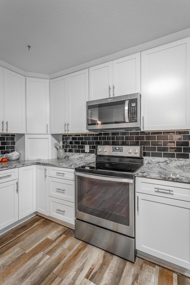 409 Caraway Turn, Chattanooga, TN 37415 - kitchen featuring appliances with stainless steel finishes, white cabinets, light stone counters, and backsplash