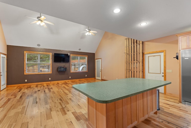 210 Gordon Dr, Chatsworth, GA 30705 - kitchen featuring a ceiling fan, vaulted ceiling, light wood-style floors, a center island, and dark countertops