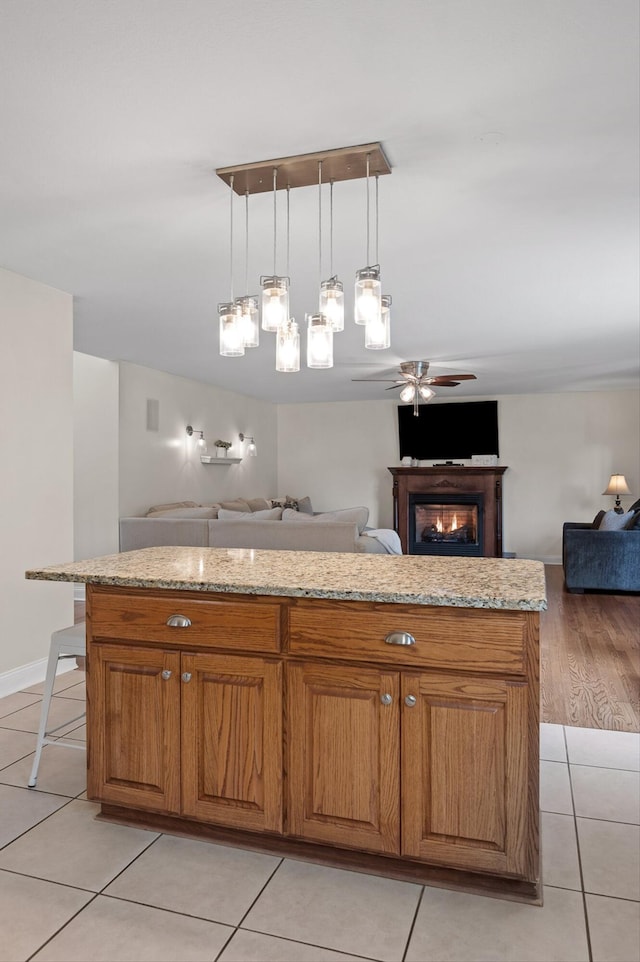 7470 Jester Ct, Ooltewah, TN 37363 - kitchen featuring open floor plan, a ceiling fan, light tile patterned floors, brown cabinets, and light stone countertops
