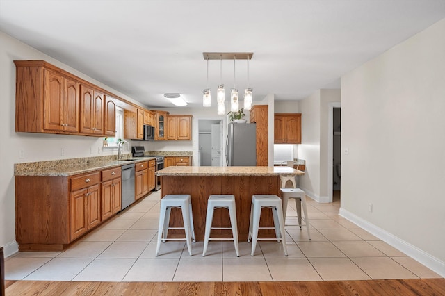 7470 Jester Ct, Ooltewah, TN 37363 - kitchen featuring stainless steel appliances, a breakfast bar, brown cabinetry, and light tile patterned flooring