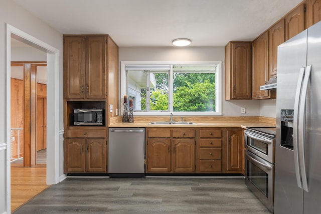 4412 Live Oak Ln, Chattanooga, TN 37411 - kitchen with appliances with stainless steel finishes, under cabinet range hood, light countertops, wood finished floors, and brown cabinetry