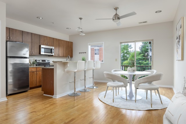 844 E 8th St, Chattanooga, TN 37403 - kitchen with stainless steel appliances, a breakfast bar area, light wood-style floors, ceiling fan, and brown cabinets