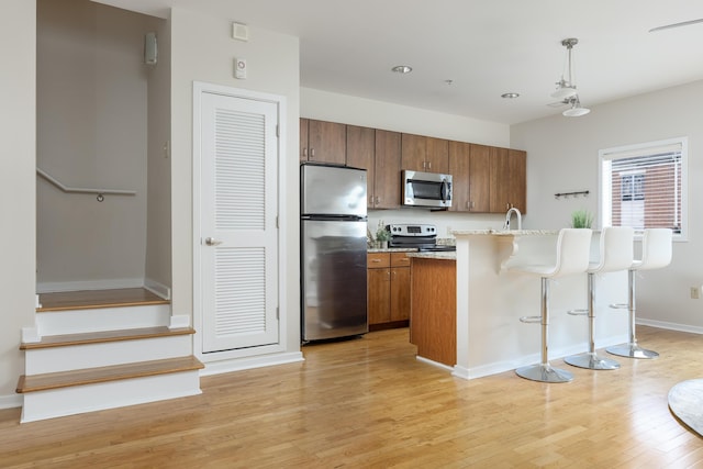 844 E 8th St, Chattanooga, TN 37403 - kitchen featuring stainless steel appliances, brown cabinets, a kitchen breakfast bar, light wood-style floors, and light countertops