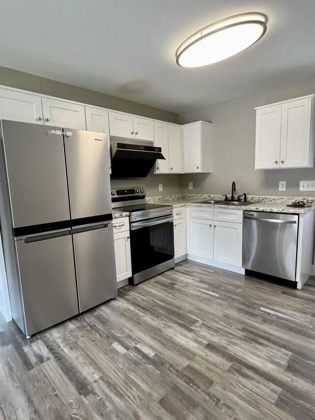 204 Roslyn Ct, Dalton, GA 30720 - kitchen featuring appliances with stainless steel finishes, light wood finished floors, under cabinet range hood, and white cabinets
