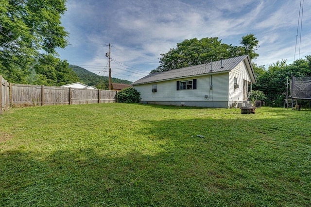 1209 Hickory Ave, South Pittsburg, TN 37380 - back of house with a trampoline, a fenced backyard, and a metal roof