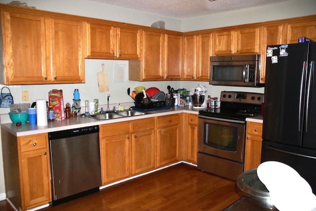 140 Chestnut Ln SE, Calhoun, GA 30701 - kitchen featuring appliances with stainless steel finishes, light countertops, brown cabinets, dark wood finished floors, and a textured ceiling