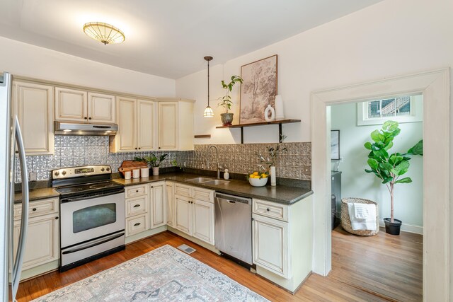 4503 Saint Elmo Ave, Chattanooga, TN 37409 - kitchen featuring appliances with stainless steel finishes, under cabinet range hood, cream cabinets, dark countertops, and tasteful backsplash