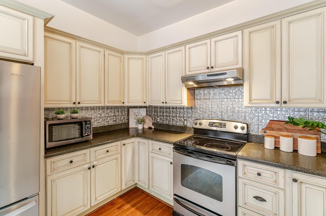 4503 Saint Elmo Ave, Chattanooga, TN 37409 - kitchen featuring cream cabinetry, stainless steel appliances, under cabinet range hood, and dark countertops