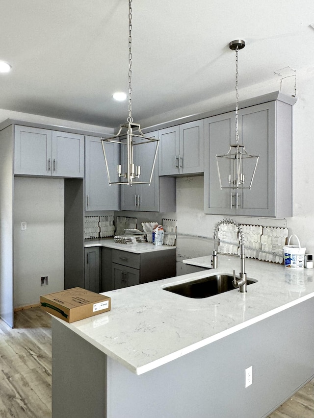 5303 Marion Ave, Chattanooga, TN 37412 - kitchen featuring a chandelier, gray cabinetry, light wood-type flooring, a peninsula, and light stone countertops