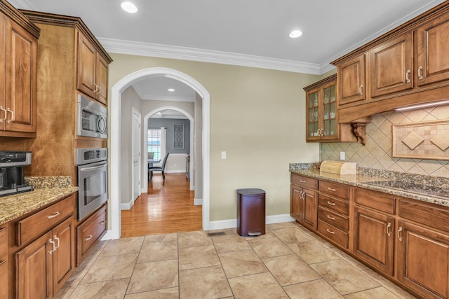 231 Turkey Run, Flintstone, GA 30725 - kitchen featuring appliances with stainless steel finishes, arched walkways, decorative backsplash, brown cabinetry, and light stone counters