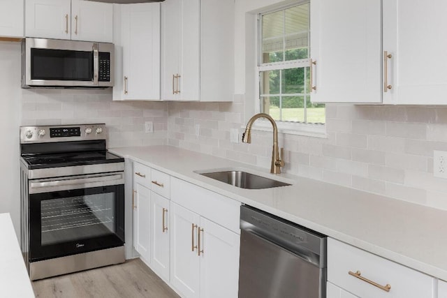 8208 Hixson Springs Rd, Signal Mountain, TN 37377 - kitchen featuring stainless steel appliances, white cabinets, light countertops, light wood finished floors, and backsplash