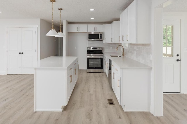 8208 Hixson Springs Rd, Signal Mountain, TN 37377 - kitchen featuring stainless steel appliances, light wood finished floors, white cabinets, light countertops, and tasteful backsplash