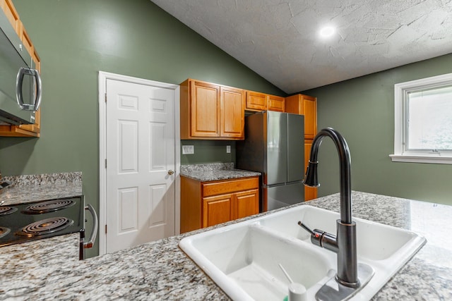 1027 Crestridge Dr, Rossville, GA 30741 - kitchen featuring freestanding refrigerator, vaulted ceiling, brown cabinetry, range with electric stovetop, and light stone counters