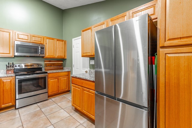 1027 Crestridge Dr, Rossville, GA 30741 - kitchen with stainless steel appliances, light tile patterned floors, and light stone countertops