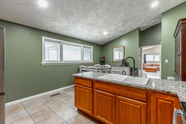 1027 Crestridge Dr, Rossville, GA 30741 - kitchen featuring healthy amount of natural light, brown cabinets, light tile patterned floors, vaulted ceiling, and recessed lighting