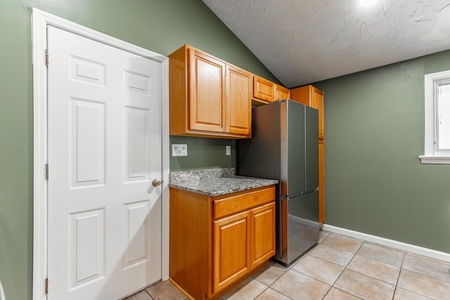 1027 Crestridge Dr, Rossville, GA 30741 - kitchen featuring freestanding refrigerator, lofted ceiling, light stone counters, light tile patterned floors, and a textured ceiling