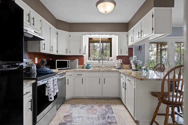 1008 Panorama Dr, Chattanooga, TN 37421 - kitchen featuring appliances with stainless steel finishes, under cabinet range hood, a peninsula, light tile patterned floors, and white cabinets