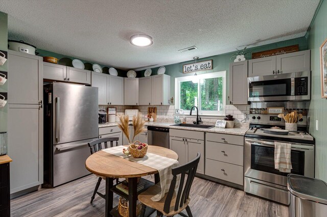 308 Pledger Pkwy, Lafayette, GA 30728 - kitchen featuring appliances with stainless steel finishes, light countertops, light wood-style floors, tasteful backsplash, and a textured ceiling